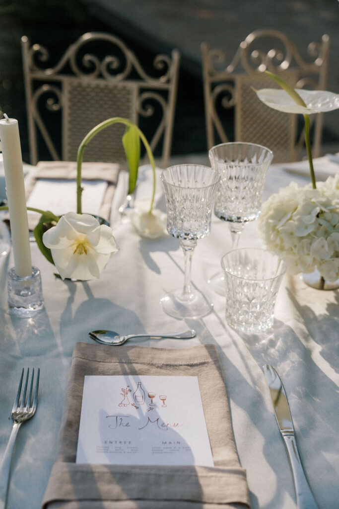Bride in Pronovias lace gown seated on silver fabric installation holding white tulip bouquet, editorial bridal shoot at La Granja Ibiza
