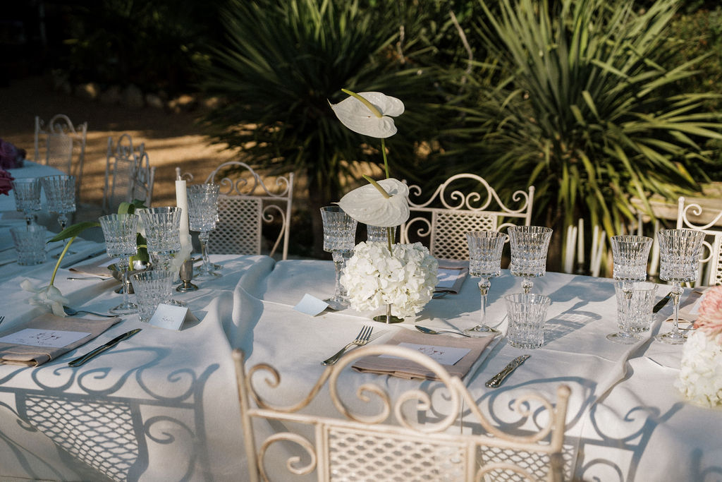Close-up of wedding place setting with illustrated menu card and linen napkin, crystal glassware, editorial wedding tablescape Ibiza