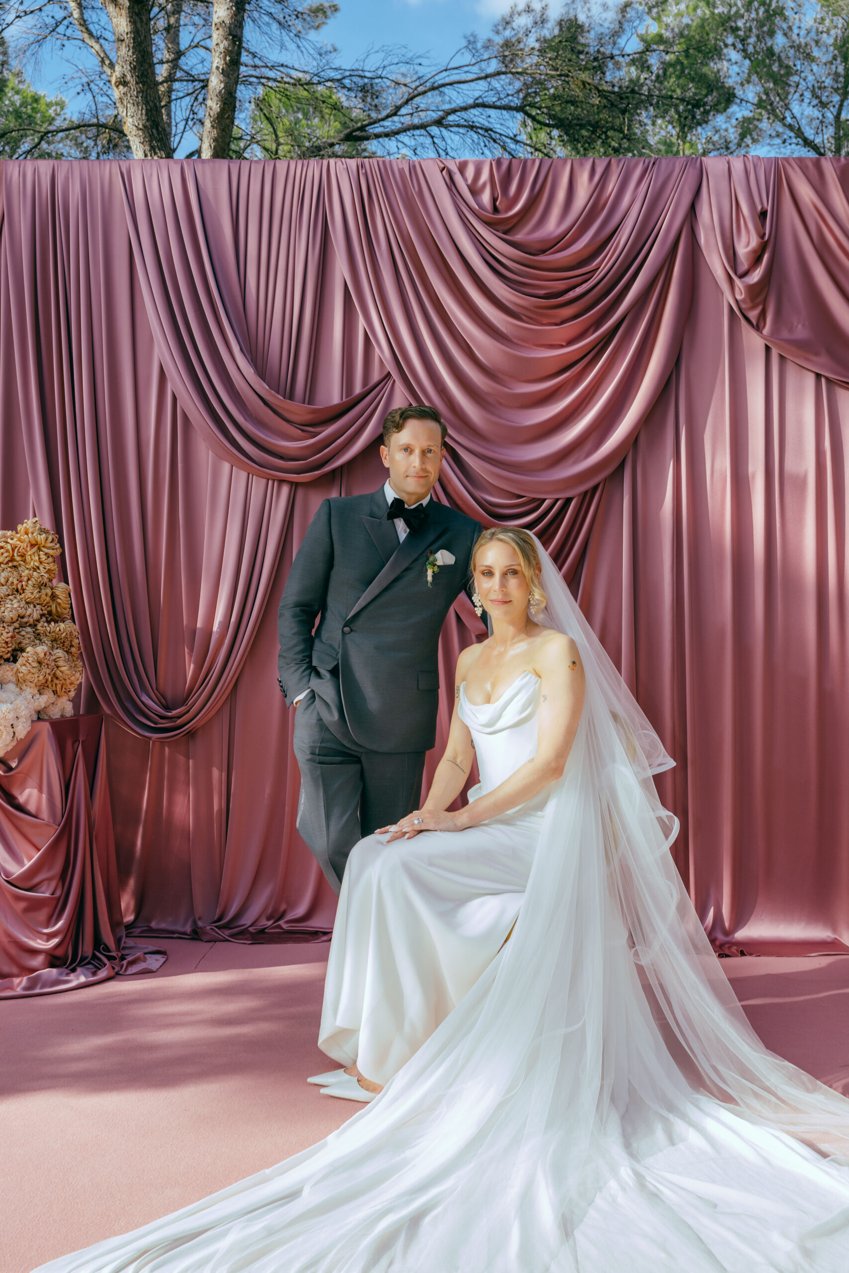 Dusty pink draped ceremony backdrop with sculptural hydrangea florals at a Ca Na Xica wedding in Ibiza.